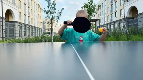 A happy young boy holds a ping-pong paddle near a table. Stock Footage 344968683