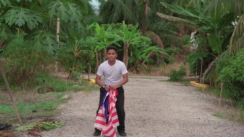 Happy young boy jumping and waving Malaysia flag or Jalur Gemilang with natur Stock Footage 111112548