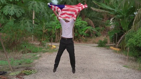 Happy young boy jumping and waving Malaysia flag or Jalur Gemilang with natur Stock Footage 111112656