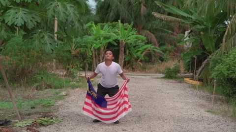 Happy young boy jumping and waving Malaysia flag or Jalur Gemilang with natur Video stock 111112942
