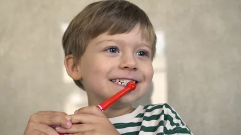 Happy young boy maintaining oral hygiene with vibrant red electric toothbrush Video stock 322173131