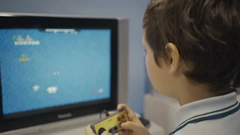 Happy young boy using a retro controller to play a video game. Stock Footage 89231770