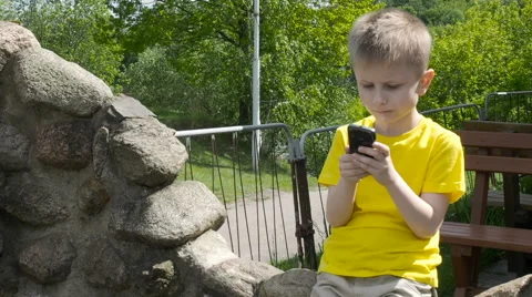 Happy young boy using smartphone in the park Stock Footage 63426516