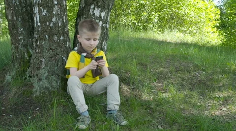 Happy young boy using smartphone in the park Stock Footage 63426711