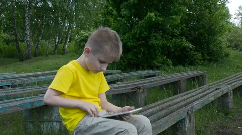 Happy young boy using tablet computer in the park Stock Footage 63405525