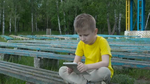 Happy young boy using tablet computer in the park Stock Footage 63406083