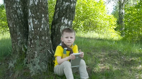 Happy young boy using tablet computer in the park Stock Footage 63407118