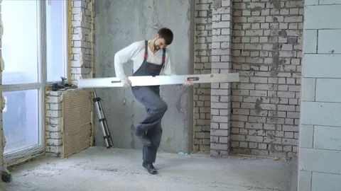 Happy young builder dancing with construction ruler imitating guitar Stock-Footage 102889386