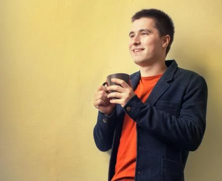 Happy young business man drinking coffee near the wall Stock Photos