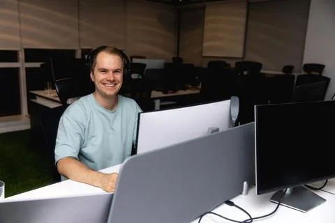 Happy young businessman using computer at his office desk. Stock Photos