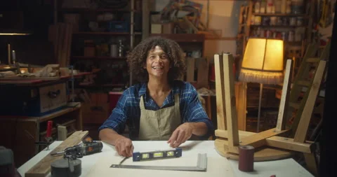 Happy young carpenter man smiling turning face to camera sitting at working desk Stock Footage 140501400