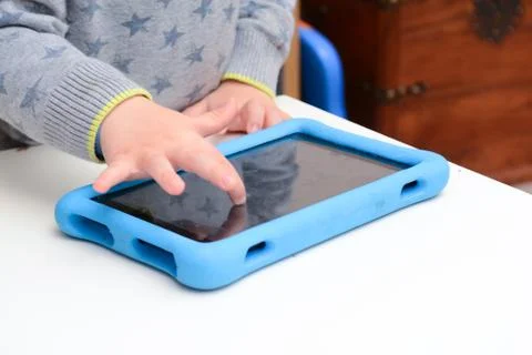 Happy young child is using a tablet computer. Boy is playing with device at h Stock Photos