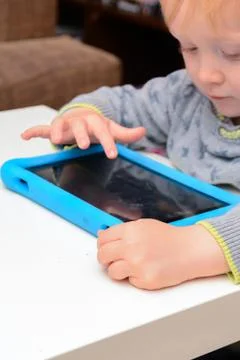 Happy young child is using a tablet computer. Boy is playing with device at h Stock Photos