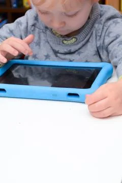 Happy young child is using a tablet computer. Boy is playing with device at h Stock Photos