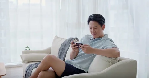 Happy young Chinese couple using smartphone in living room,4K Stock Footage 119071531