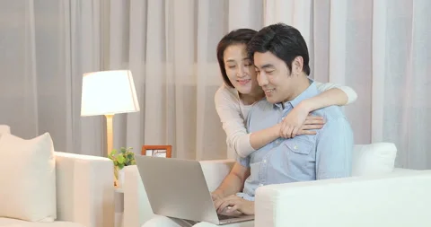 Happy young Chinese couple using laptop in living room,4K Stock Footage 151088647