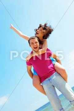 Happy young couple in casual cloths at the beach in sunny weather Stock Photos