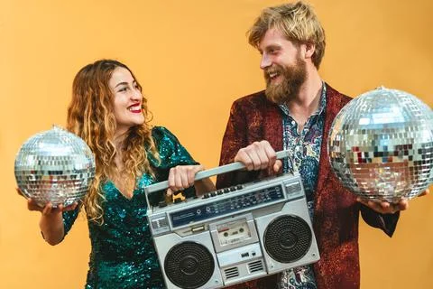Happy young couple celebrating holidays listening music with vintage boombox Stock Photos