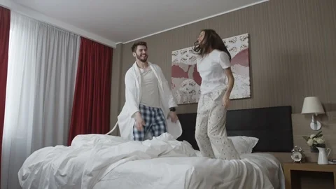 Happy young couple is dancing and jumping on bed in the morning Stock Footage 73349236