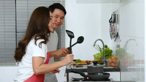Happy young couple dancing and cooking and preparing food in the kitchen at home Stock Footage 170710567