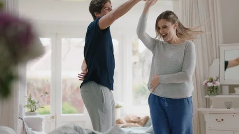 Happy young couple dancing at home smiling enjoying celebrating lifestyle in mid Stock Footage