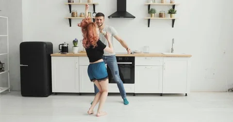 Happy young couple dancing in kitchen wearing pajamas listening to music morning Stock Footage 103312391