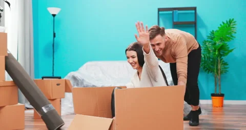 Happy young couple first time home buyers having fun unpacking laughing on Stock Footage