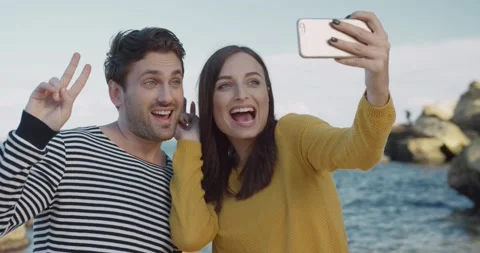 Happy young couple grimaces while holding smartphone in hand and making cheerful Stock Footage 147061321