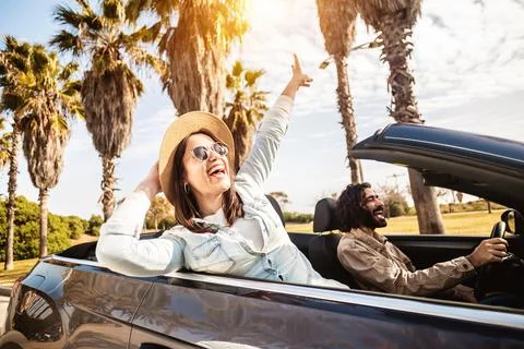 Happy young couple having enjoying summer vacation on convertible car Stock Photos