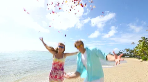 Happy young couple having fun with plenty of rose petals on beach Stock Footage 58172153