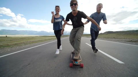 Happy young couple having fun with skateboard on the road. Young man and woman Stock Footage 65483851