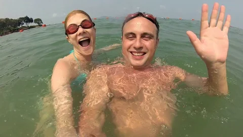 Happy young couple having fun in sea. Waving to camera diving. Vacation summer Stock Footage 75046493