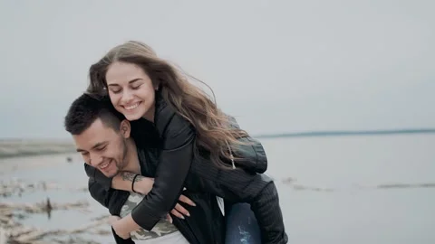 Happy young couple having fun on the seashore on a cloudy day. A beautiful girl Video stock 139876876