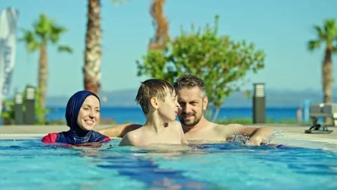 Happy young couple having fun in the pool with their son. Video stock 156854640