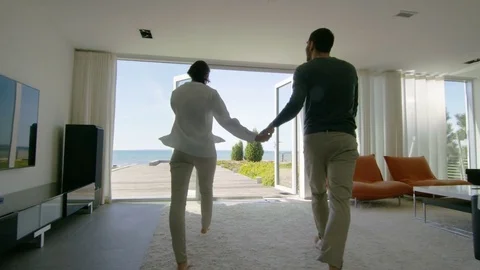 Happy Young Couple Holding Hands  Runs out of Their Home onto the Terrace Stock Footage
