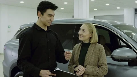 Happy young couple hugging while sitting in a new car model in the dealership Stock Footage 323175485