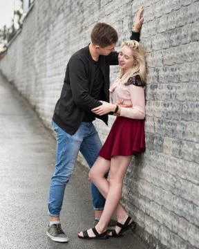 Happy young couple hugging while standing near gray wall Stock Photos
