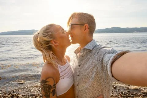 Happy Young Couple Kissing and Taking Selfie At Beach Stock Photos