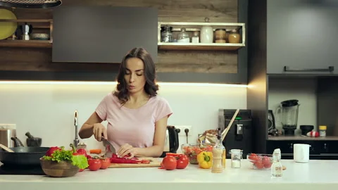 Happy young couple at the kitchen, Man having fun and taking peace of vegetable. Stock Footage 100303248