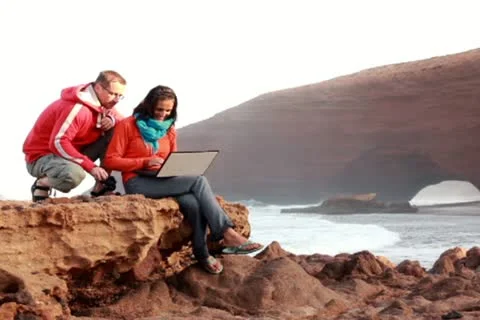Happy young couple with laptop computer on beautiful Legzira beach Stockbeeldmateriaal 10891580