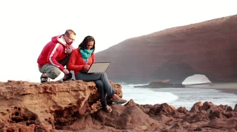 Happy young couple with laptop computer on beautiful Legzira beach 库存影片 10891896