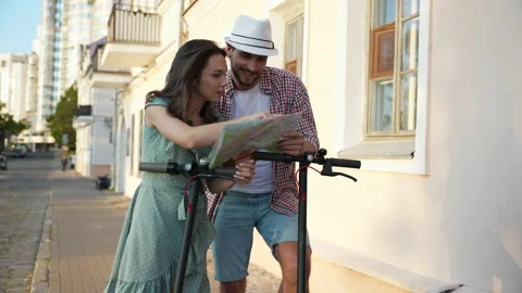 Happy young couple looking at the map while coming as tourists to the new city Stock Footage 232369639