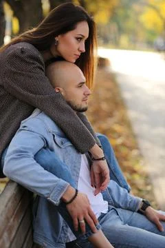 Happy young couple looking in the same direction on a park bench, smiling. Stock Photos