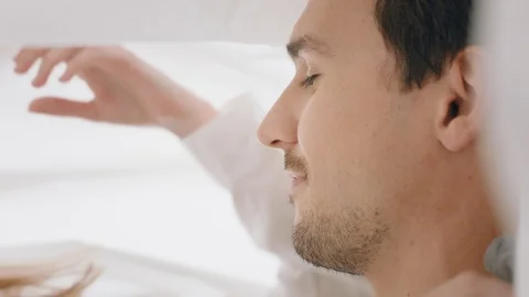 Happy young couple lying in bed kissing under sheets sharing romantic Stock Footage 109514078