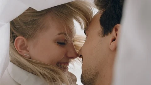 Happy young couple lying in bed kissing under sheets sharing romantic Stock Footage 109514084