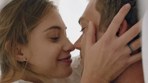 Happy young couple lying in bed kissing under sheets sharing romantic Stock Footage 111737235