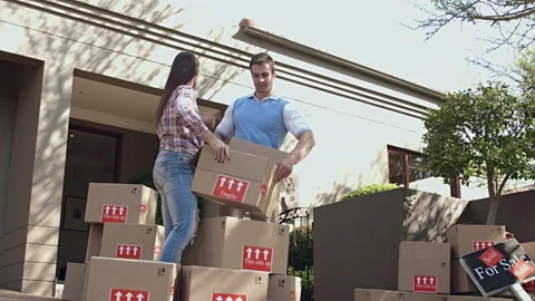 Happy young couple moving/ sorting their boxes while moving into a new house Видео 199631966