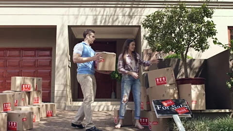 Happy young couple moving/ sorting their boxes while moving into a new house Видео 199631976