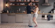Happy Young Couple Newly Wed Dancing Listening To Music In Kitchen Wearing Stock Footage