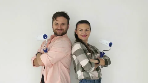 Happy young couple with paint rollers near white wall Stock Footage 122554837